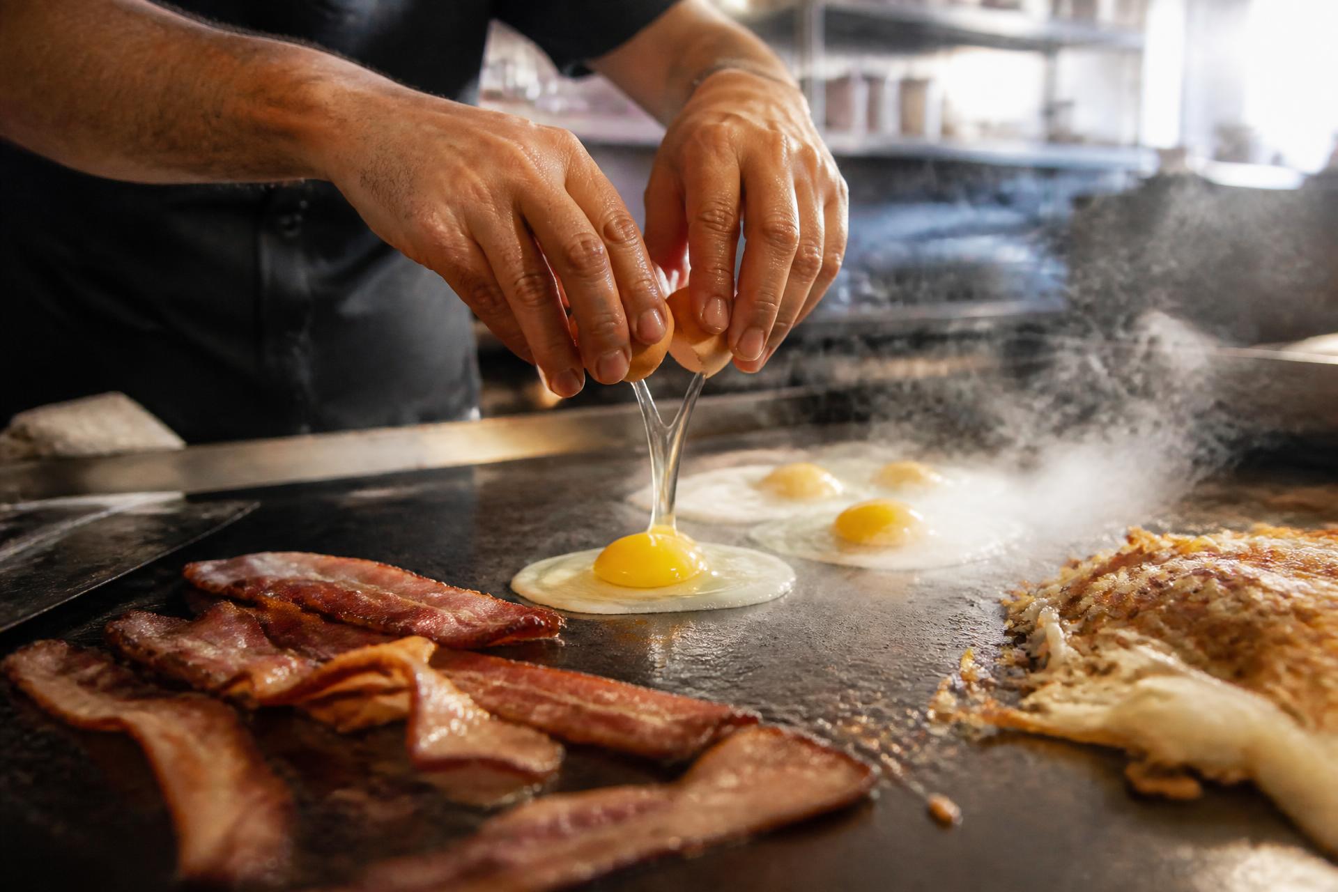 Short-order cook preparing breakfast plates on a flat-top grill